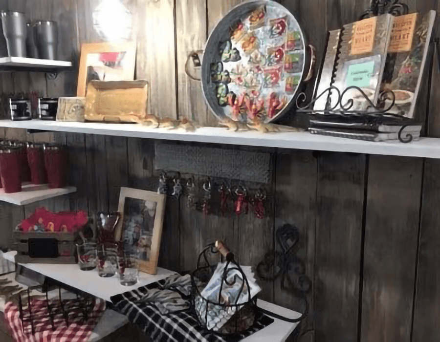 A rustic display of home decor items, including framed photos, kitchenware, and colorful cups, on wooden shelves.