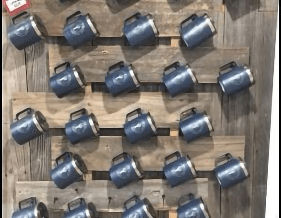 A mounted display features multiple blue mugs arranged neatly on a wooden background.