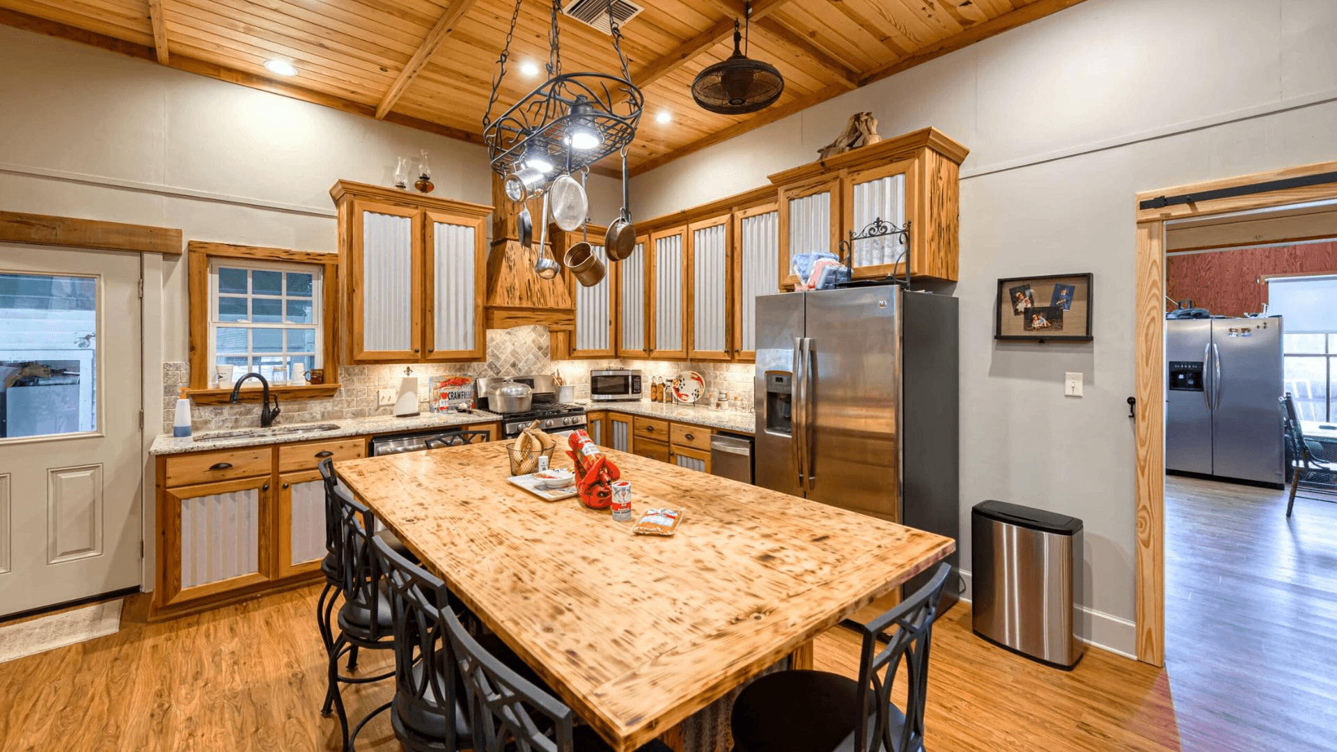 A cozy kitchen featuring wooden cabinets, a large table, and modern appliances.