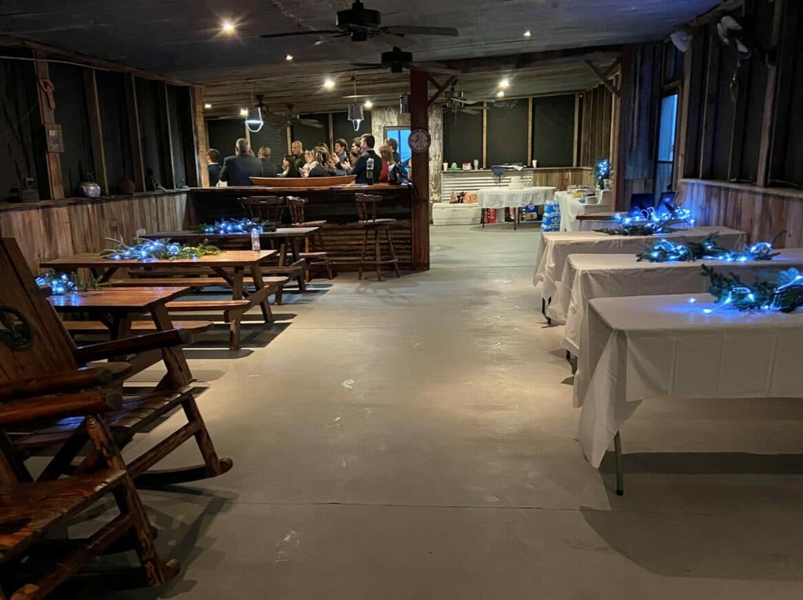A dimly lit party venue featuring wooden tables, a bar area, and blue decorative lights.