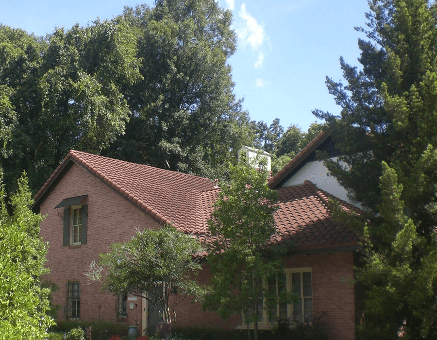 A charming brick house surrounded by lush trees and greenery.