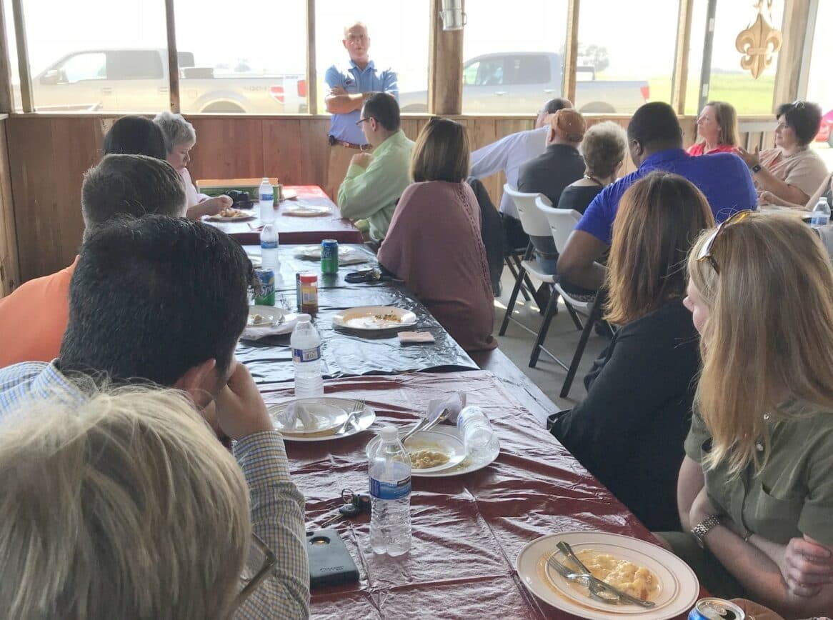 A group of people seated at tables listens to a speaker in a casual dining setting.