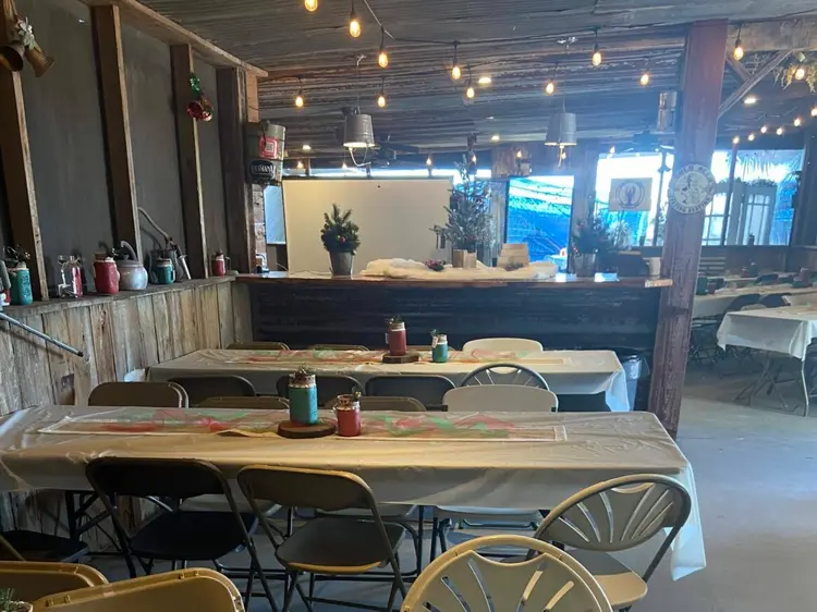 A rustic dining area with wooden walls, decorated tables, and string lights overhead.