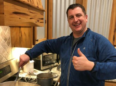 man holding thumbs up while stirring gumbo
